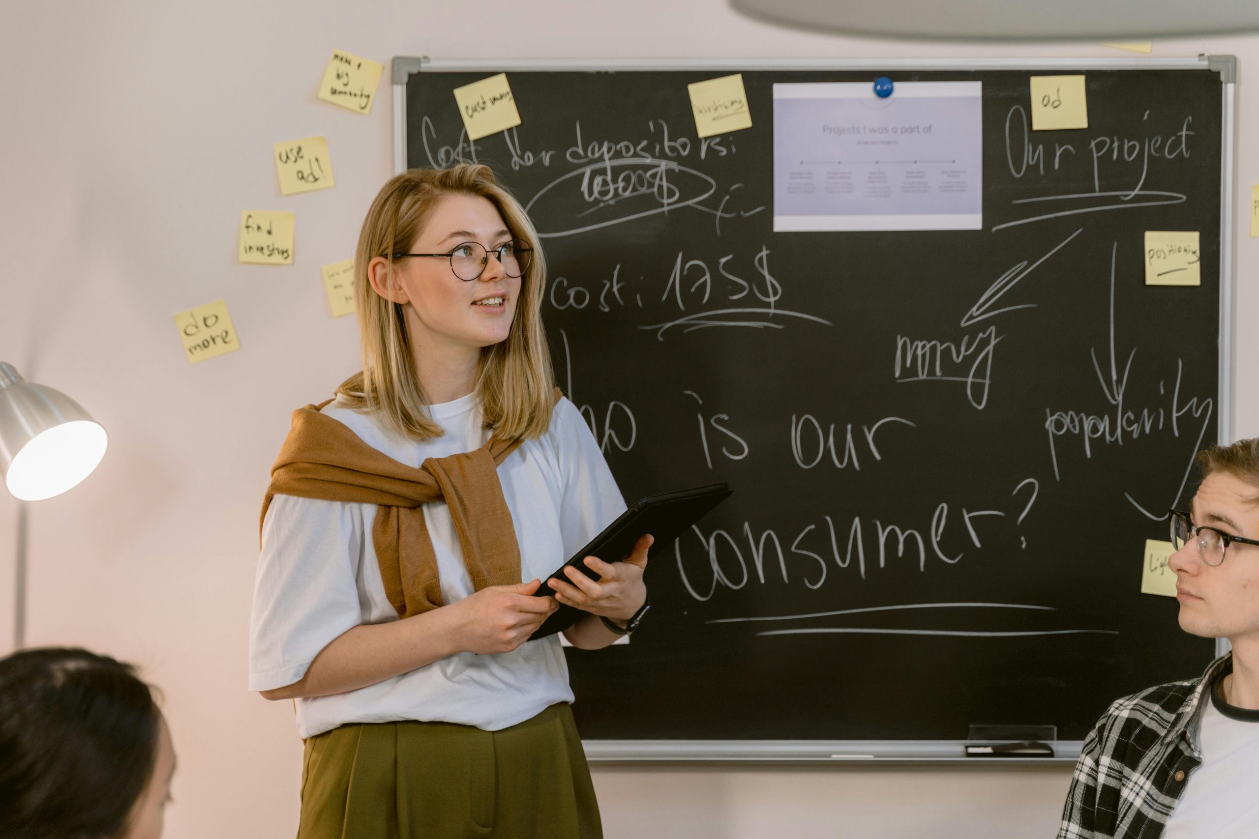 employees in a meeting, with a blackboard displaying 'who is our customer' in front of them